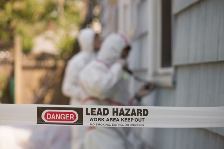 Two hazmat workers chipping off lead paint